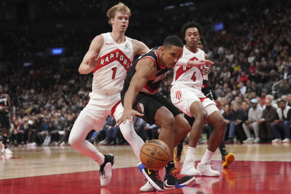 Portland Trail Blazers guard Malcolm Brogdon, center, and Toronto Raptors guard Gradey Dick (1) battle for the ball during second-half NBA basketball game action in Toronto, Monday, Oct. 30, 2023. (Nathan Denette/The Canadian Press via AP)