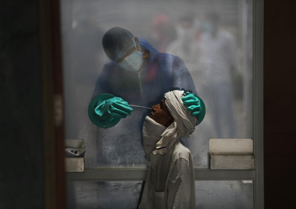 A health worker takes a nasal swab of a person for a COVID-19 test at a hospital in New Delhi, India, Monday, July 6, 2020. (AP Photo/Manish Swarup)