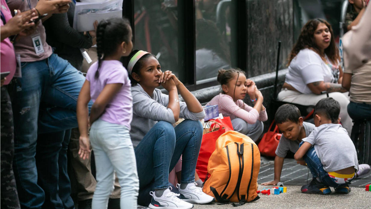 Migrants sit and stand outside the Roosevelt Hotel in New York City.