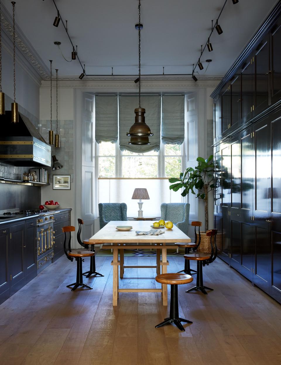 Plain English cabinetry painted in Pure & Original’s Aubergine and Ristretto create a moody focal point that’s offset by zellige Emery & Cie tiles in the kitchen. The pendant lights by Felix Lighting hang above a bespoke table by Matthew Cox and against a backdrop of Farrow & Ball’s Elephant’s Breath, Dove Tale, and Dimity on the respective walls, woodwork, and ceiling.