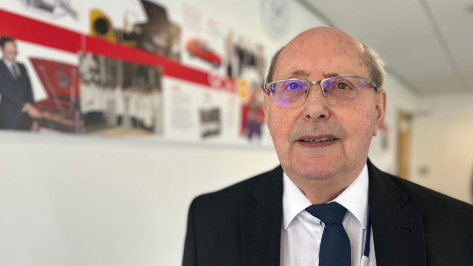 Dennis Webster wearing a blue blazer and white shirt looking at the camera