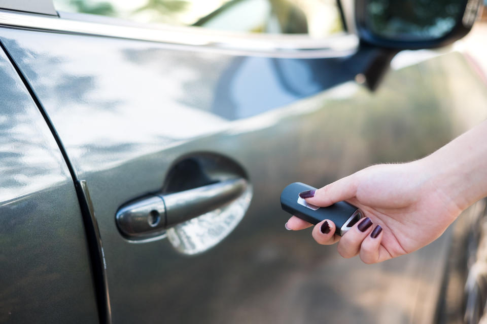 A woman unlocks her car with a key