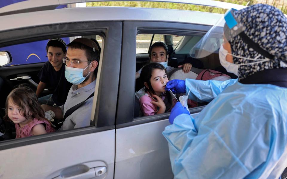 A medical worker performs a Covid-19 test on a child at a drive-through testing centre in Jerusalem, Israel on 29 July 2021 - Menahem Kahana/AFP