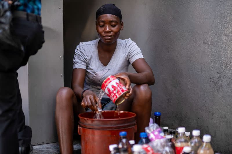 A gasoline street vendor pours gasoline from a bucket into used soft drink bottles following the assassination of President Jovenel Moise, in Port-au-Prince