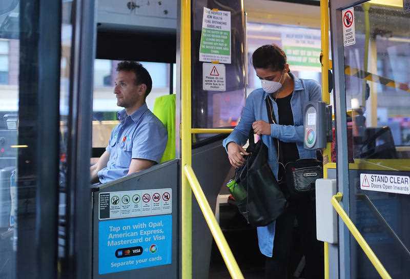 A woman wearing a mask as a preventative measure against the coronavirus disease (COVID-19) boards a public bus at Railway Square bus station in Sydney.