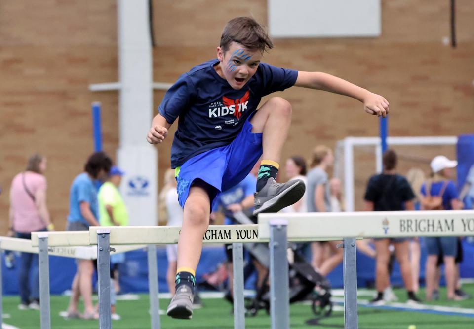 Carter Ernst does his best to clear the hurdles inside the Indoor Practice Facility as BYU holds a party to celebrate their move into the Big 12 Conference with music, games and sports exhibits in Provo on Saturday, July 1, 2023. | Scott G Winterton, Deseret News