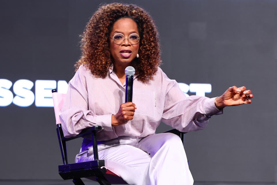 Close-up of Oprah sitting onstage and holding a microphone