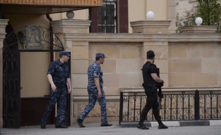 Law enforcement officers walk outside an Orthodox church after the attack of militants in Grozny, Russia May 19, 2018. REUTERS/Said Tsarnayev