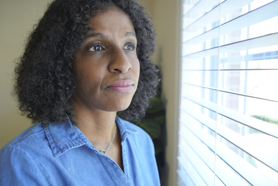 Tamika Dalton looks out of a window at her home in Durham, N.C., on Sept. 23, 2021. When COVID-19 kept visitors from going inside the Blumenthal Nursing and Rehabilitation Center in Greensboro, N.C, Dalton would often visit at her mother’s window a couple times a day. Through the glass, Dalton didn’t like what she saw: Fewer and fewer aides passed by, and her mother sometimes sat for hours in a soiled diaper. (AP Photo/Allen G. Breed)