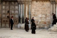 Roman Catholic monks pray in front of the locked door of Jerusalem's Church of the Holy Sepulchre amid coronavirus restrictions in the walled Old City