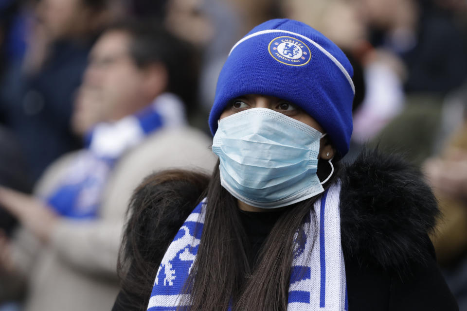 Chelsea's fan wears a sanitary mask during the English Premier League soccer match between Chelsea and Everton at Stamford Bridge stadium in London, Sunday, March 8, 2020. (AP Photo/Matt Dunham)