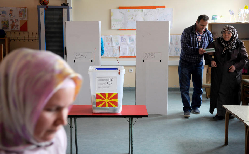 An elderly ethnic Albanian woman, right, is helped by a relative to casts her ballot for the presidential elections in Skopje, Macedonia, on Sunday, April 13, 2014. Macedonia votes on the fifth presidential elections since the country's independence. (AP Photo/Boris Grdanoski)