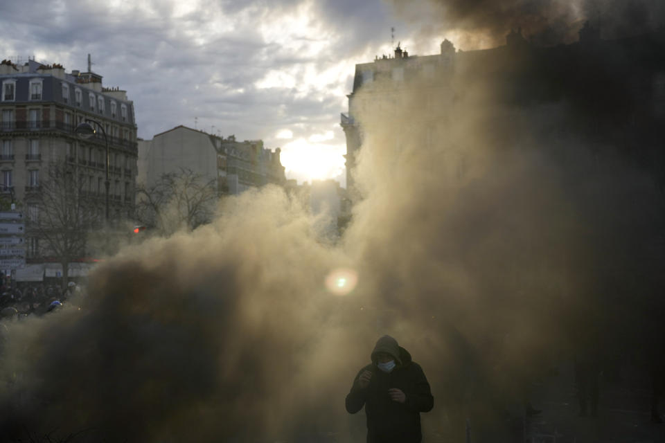 A man emerges from a cloud of smoke after a demonstration Tuesday, March 28, 2023 in Paris. It's the latest round of nationwide demonstrations and strikes against unpopular pension reforms and President Emmanuel Macron's push to raise France's legal retirement age from 62 to 64. (AP Photo/Thibault Camus)