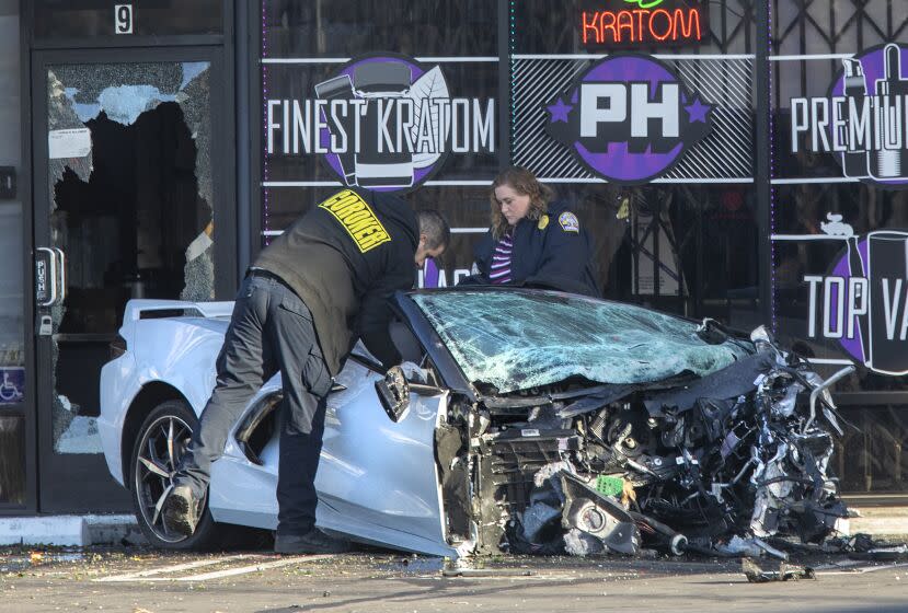 VAN NUYS, CA-FEBRUARY 8, 2023:Members of the Los Angeles County Coroner's office look at the remains of a Chevy Corvette that ended up in a shopping center after crashing into a Honda Accord at the intersection of Balboa Blvd. and Victory Blvd. in Van Nuys. According to LAPD Sgt. Hector Gutierrez, at approximately 3:45 am this morning, the driver of the Corvette, a male, was traveling an estimated 90 to 100 mph, heading north on Balboa Blvd. and crashed into a Honda Accord, driven by a woman in her forties, traveling east on Victory Blvd. Both drivers of the cars died as a result. It is believed that the driver of the Corvette went through a red light. The passenger in the Corvette, a male, was taken to a hospital with severe injuries. There were no passengers in the Honda Accord. (Mel Melcon / Los Angeles Times)