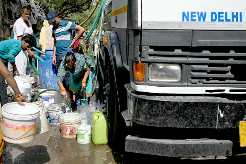 People fill their containers with water distributed by a municipal tanker in Delhi (AFP via Getty)