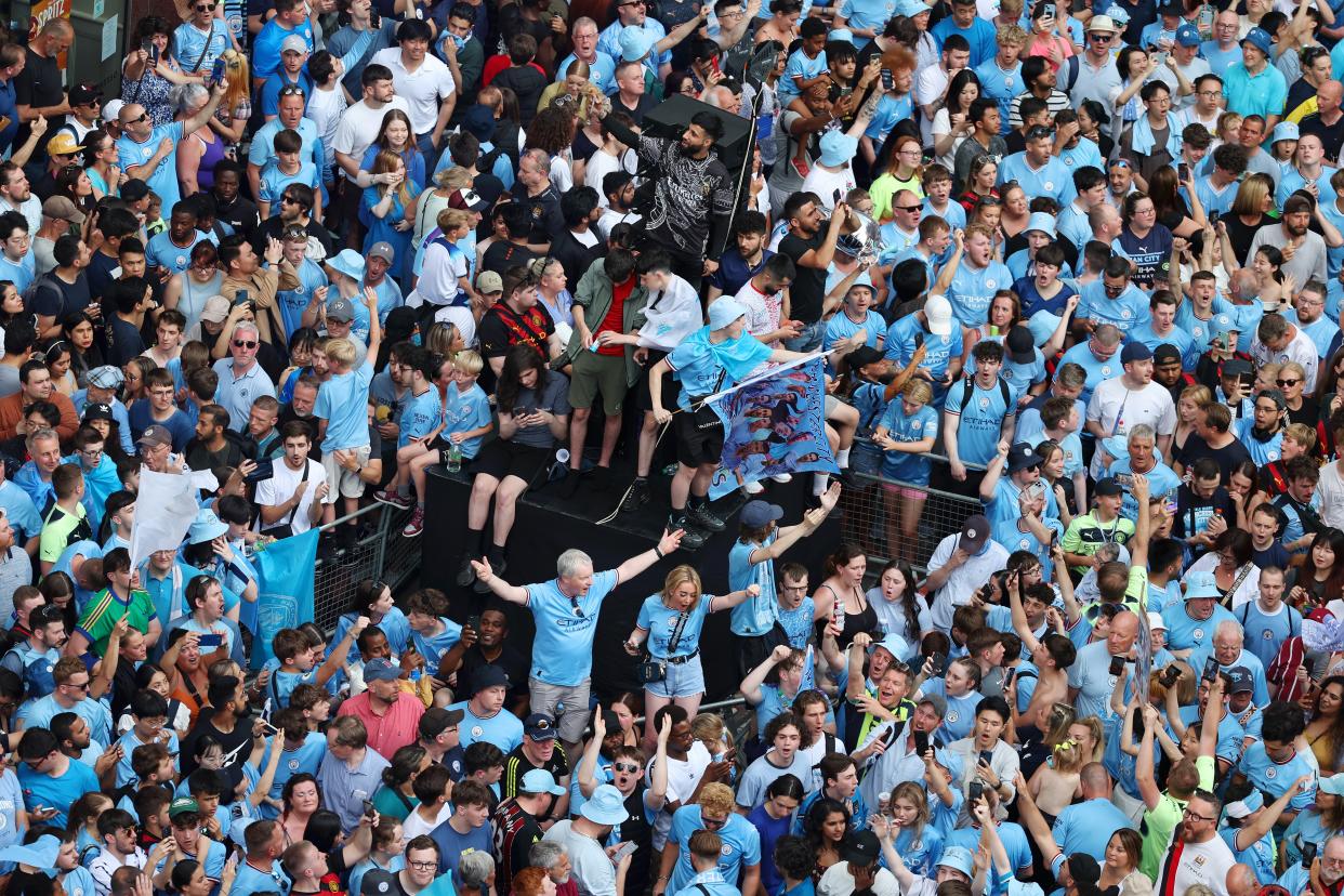 Manchester City fans take shelter from the rain ahead of the Treble Parade in Manchester. (Manchester City FC via Getty Ima)