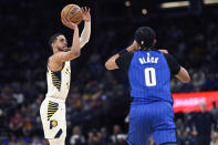 Indiana Pacers guard Tyrese Haliburton, left, shoots a 3-pointer as Orlando Magic guard Anthony Black (0) defends during the first half of an NBA basketball game, Sunday, March 10, 2024, in Orlando, Fla. (AP Photo/Phelan M. Ebenhack)