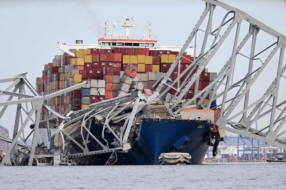 A large cargo ship under debris from a fallen bridge.