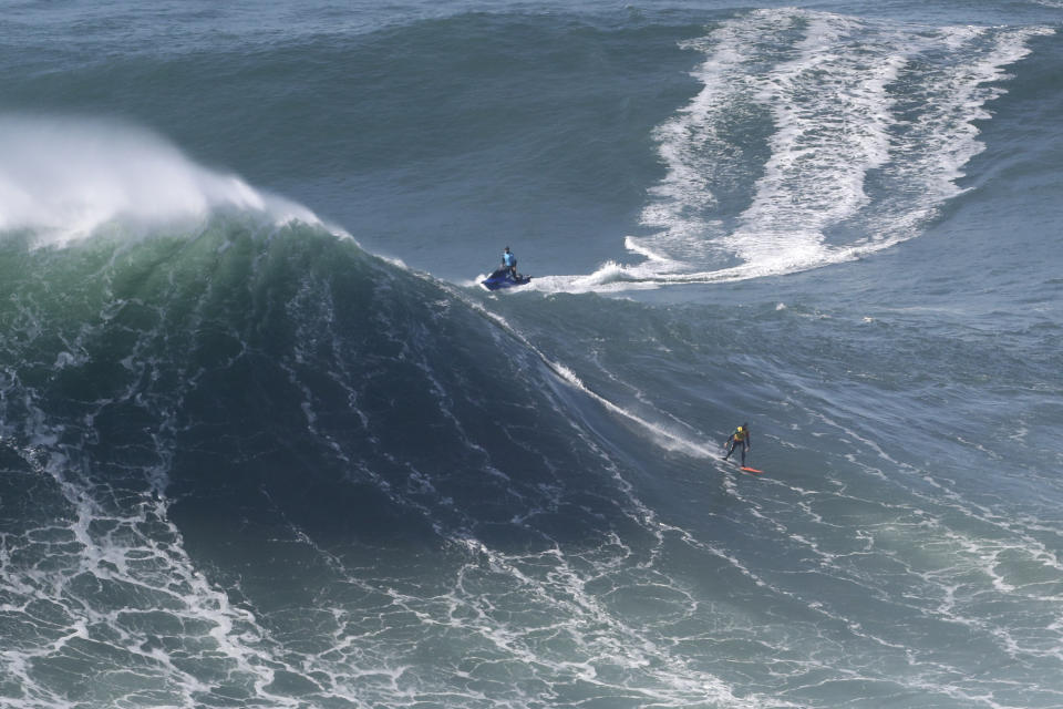 A surfer rides a wave during a tow surfing session at Praia do Norte or North Beach in Nazare, Portugal, Thursday, Oct. 29, 2020. A big swell generated earlier in the week by Hurricane Epsilon in the North Atlantic, reached the Portuguese west coast drawing big wave surfers to Nazare. (AP Photo/Pedro Rocha)