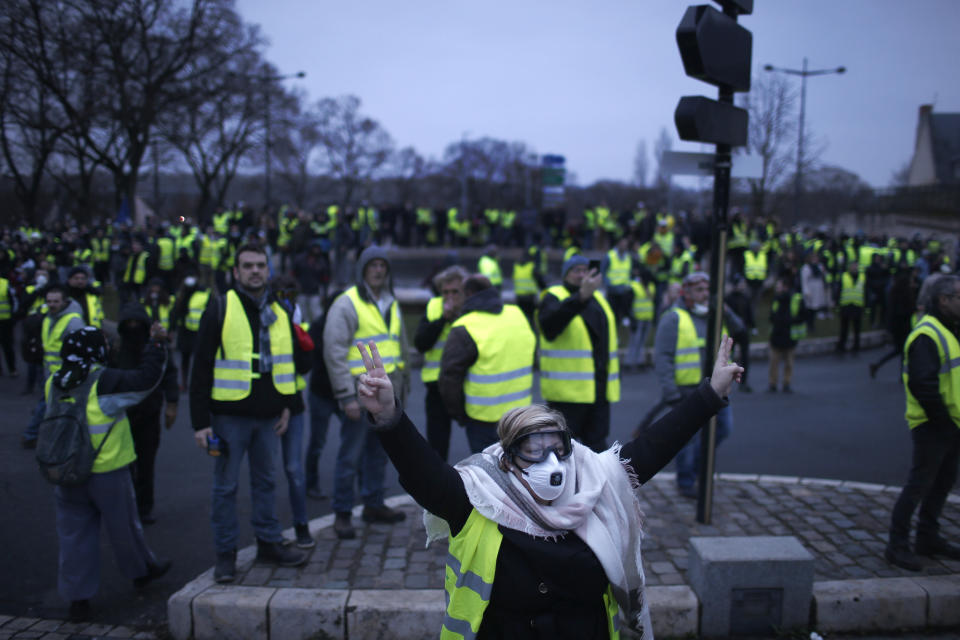 A yellow vest protestor flashes a v-sign during a demonstration in Bourges, central France, Saturday, Jan. 12, 2019. Paris brought in armored vehicles and the central French city of Bourges shuttered shops to brace for new yellow vest protests. The movement is seeking new arenas and new momentum for its weekly demonstrations. Authorities deployed 80,000 security forces nationwide for a ninth straight weekend of anti-government protests. (AP Photo/Rafael Yaghobzadeh)