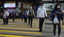 People wearing face masks walk at a down town street in Hong Kong Wednesday, March 25, 2020. For most, the coronavirus causes only mild or moderate symptoms, such as fever and cough. But for a few, especially older adults and people with existing health problems, it can cause more severe illnesses, including pneumonia. (AP Photo/Vincent Yu)