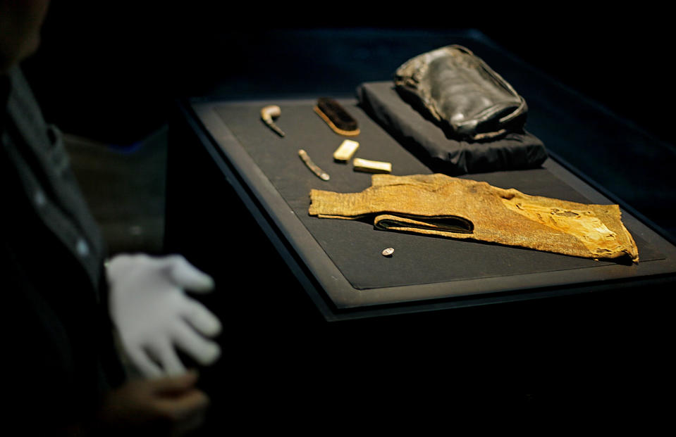 The personal effects of William Murdoch, the bridge officer aboard the Titanic, are seen as Alexandra Klingelhofer, vice president of collections for Premier Exhibitions, Inc., takes off a white glove after handling the items before an exhibition opens to the public Tuesday, April 3, 2012, in Atlanta. From the pitch-black depths 2½ miles beneath the North Atlantic, salvagers of the Titanic made a notable discovery when they located the personal effects of Murdoch, the bridge officer who tried in vain to keep the doomed ship from colliding with an iceberg. The artifacts, including a shoe brush, straight razor and pipe, are the first to be specifically to Murdoch, a central figure in the disaster who gained added notoriety after James Cameron’s polemical portrayal of him in the 1997 blockbuster movie “Titanic.” (AP Photo/David Goldman)