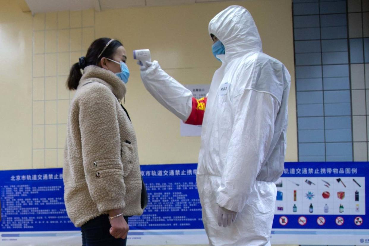 Taking precautions: with fears growing that the coronavirus will spread from China, a health official checks a woman's temperature on the underground in Beijing: Getty Images