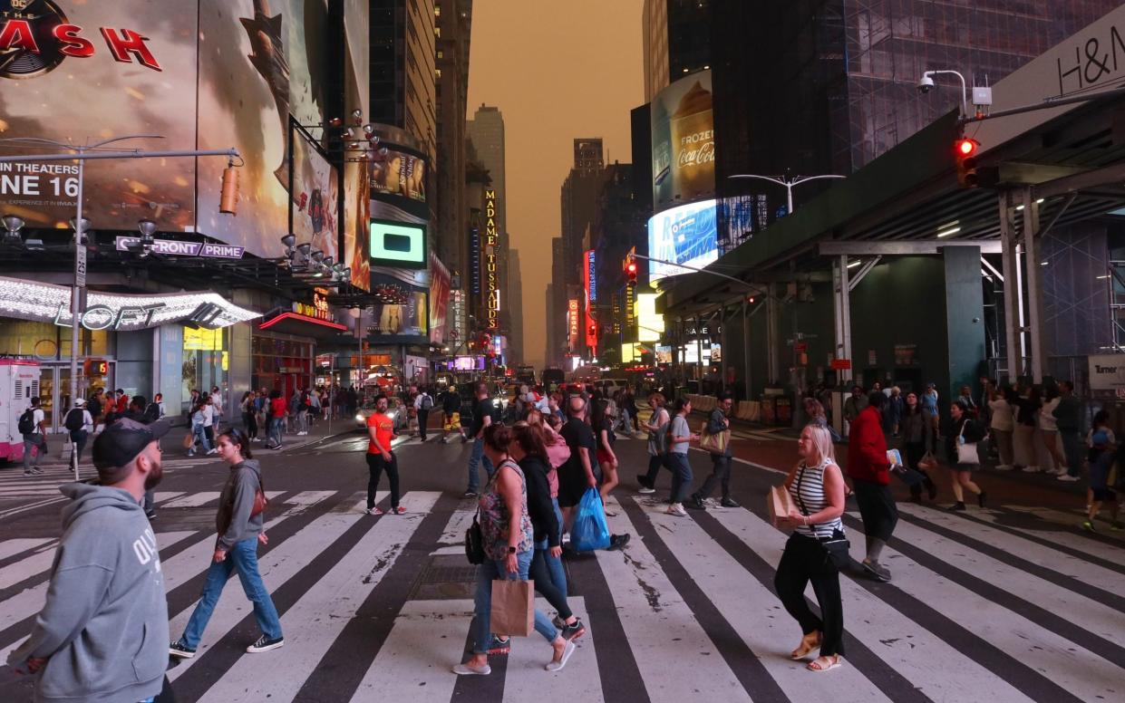 Heavy smoke turns the sky yellow as people walk across 42nd Street in Times Square - Gary Hershorn