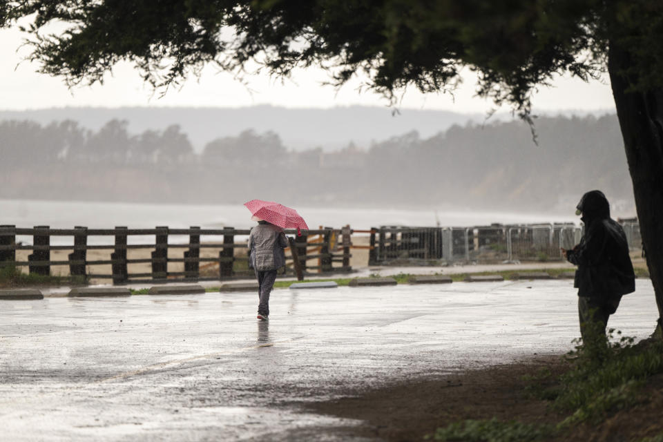 People walk through wet conditions along Seacliff State Beach in Aptos, Calif., Wednesday, Dec. 20, 2023. (AP Photo/Nic Coury)