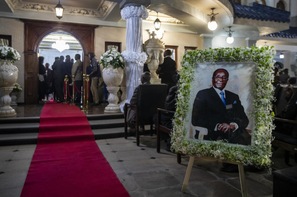 FILE - In this Wednesday, Sept. 11, 2019 file photo, a portrait of former president Robert Mugabe stands outside the room where his body lies in state inside his official residence in the capital Harare, Zimbabwe. These African stories captured the world's attention in 2019 - and look to influence events on the continent in 2020. (AP Photo/Ben Curtis, File)