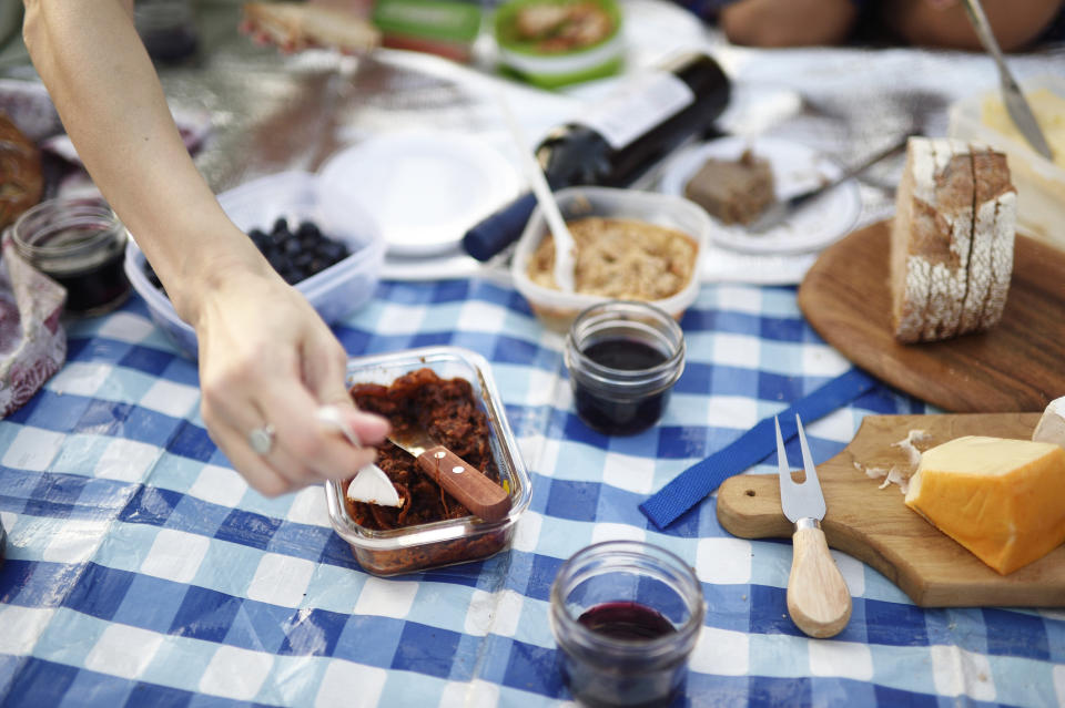 Hands reaching for food at a picnic.