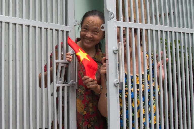 A woman waves a flag as US President Barack Obama's motorcade passes by in Vietnam's Ho Chi Minh City on May 24, 2016