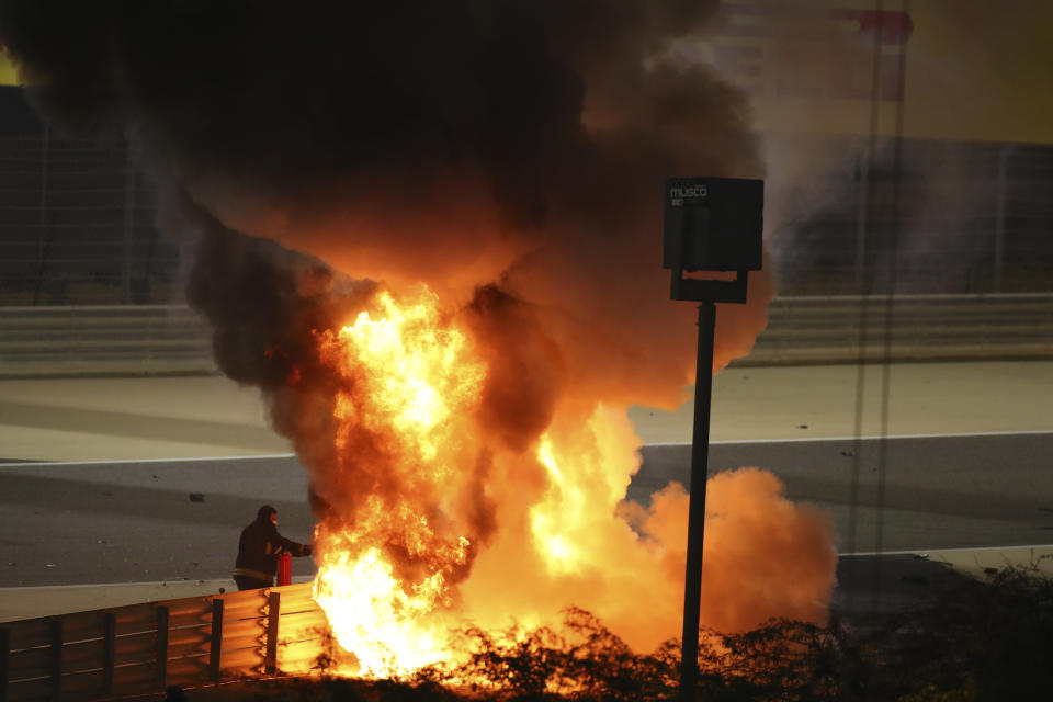 Staff extinguish flames from Haas driver Romain Grosjean of France's car after a crash during the Formula One race in Bahrain International Circuit in Sakhir, Bahrain, Sunday, Nov. 29, 2020. (Brynn Lennon, Pool via AP)