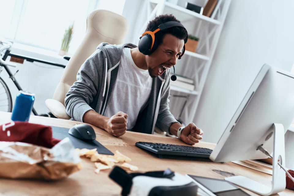 A man yelling into a headset looking at a computer.