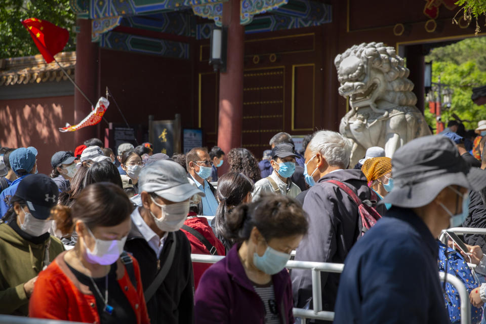 Visitors wearing face masks wait in line to enter a public park in Beijing, Saturday, May 1, 2021. Chinese tourists are expected to make a total of 18.3 million railway passenger trips on the first day of the country's five-day holiday for international labor day, according to an estimate by the state railway group, as tourists rush to travel domestically after the coronavirus has been brought under control in China.(AP Photo/Mark Schiefelbein)
