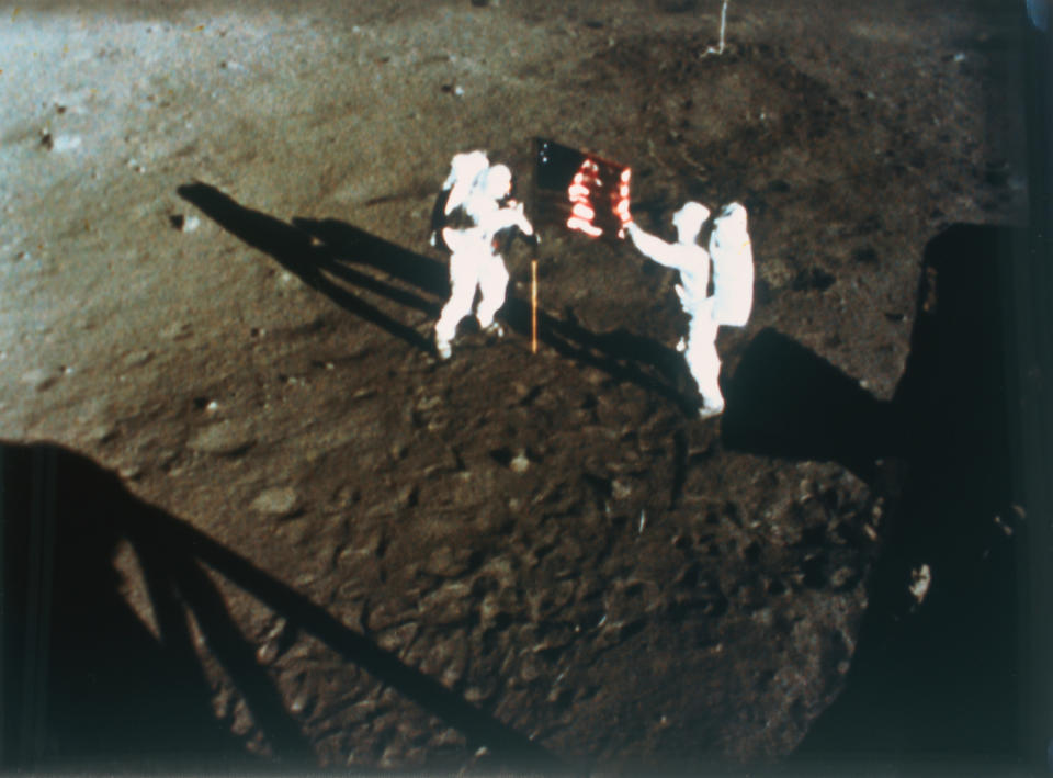 Two astronauts planting an American flag on the moon