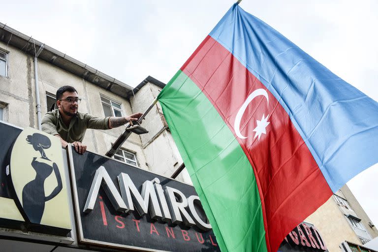 Un residente de Bakú cuelga una bandera de Azerbaiyán en apoyo a la ofensiva sobre Nagorno Karabaj