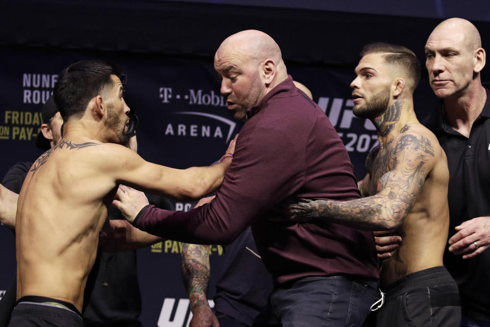 UFC president Dana White, center, gets between Dominick Cruz, left, and Cody Garbrandt during an event for UFC 207, Thursday, Dec. 29, 2016, in Las Vegas. The two are scheduled to fight in a mixed martial arts bantamweight championship bout Saturday in Las Vegas. (AP Photo/John Locher)