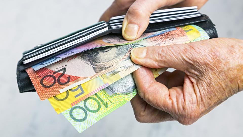 Close-up senior female hands taking Australian banknotes from purse