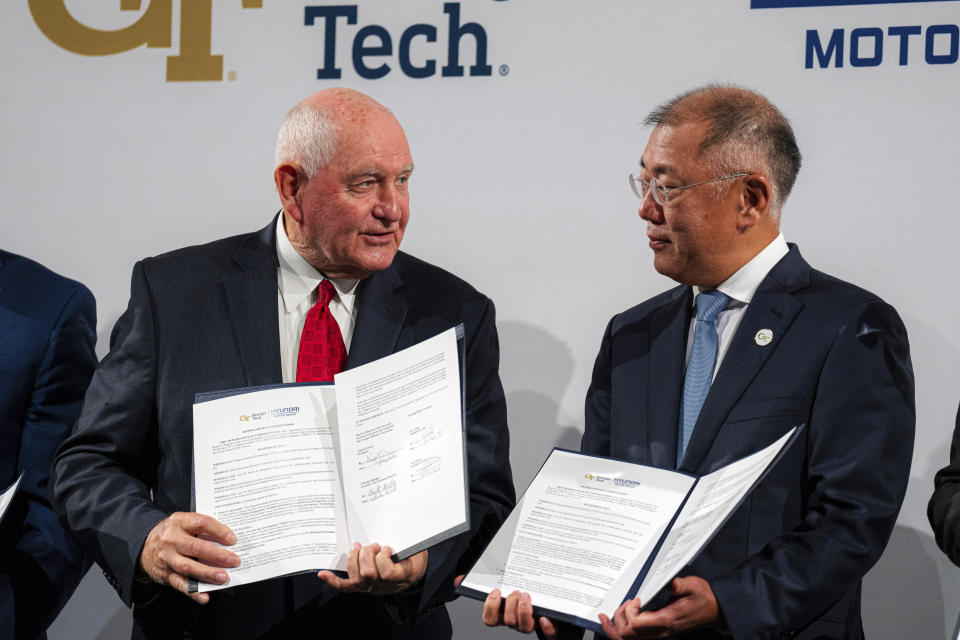 CORRECTS ID TO HYUNDAI MOTOR GROUP EXECUTIVE CHAIRMAN EUISUN CHUNG, NOT HYUNDAI MOTOR COMPANY CEO JAY CHANG - Chancellor of the University System of Georgia Sonny Perdue, left, and Hyundai Motor Group Executive Chairman Euisun Chung hold up a new memorandum of understanding for future mobility collaboration during a ceremony at Georgia Tech in Atlanta, Tuesday, Sept. 19, 2023. ((Matthew Pearson/WABE via AP)