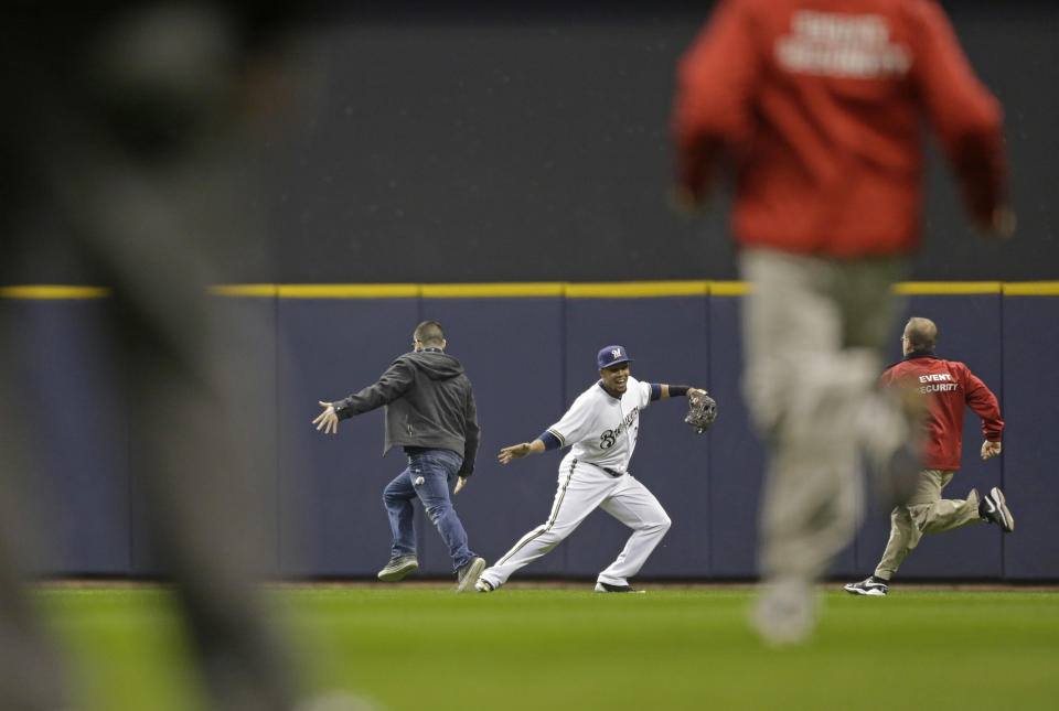 Carlos Gomez #27 of the Milwaukee Brewers low-fives a fan who ran onto the playing field in the third inning of a game against the Atlanta Braves at Miller Park on April 1, 2014 in Milwaukee, Wisconsin. (Photo by Jeffrey Phelps/Getty Images)