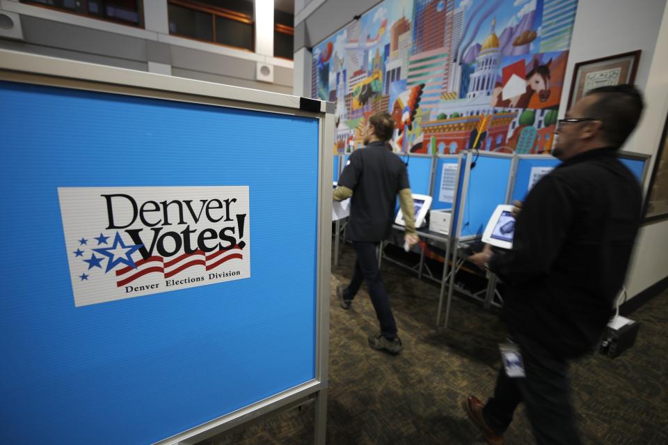 An election judge, left, leads a voter to a machine to cast a ballot at the Denver Elections Division Tuesday, May 7, 2019, in Denver. Voters could make Denver the first U.S. city to decriminalize the use of psilocybin, the psychoactive substance in "magic mushrooms" if the measure passes. (AP Photo/David Zalubowski)