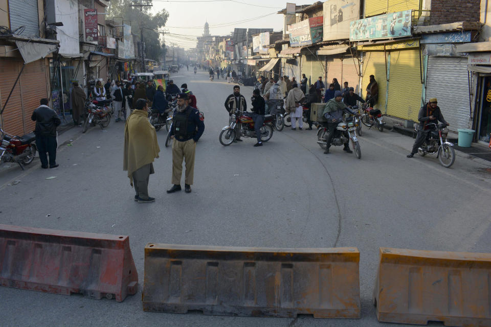 Security officials stand guard on a blocked road leading to a counter-terrorism center where several Pakistani Taliban detainees have taken police officers and others hostage inside the compound, in Bannu, a district in the Pakistan's Khyber Pakhtunkhwa province, Monday, Dec. 19, 2022. Several Pakistani Taliban detainees have managed to overpower their guards at the counter-terrorism center, snatching police weapons and taking control of the facility, officials said Monday. (AP Photo/Muhammad Hasib)