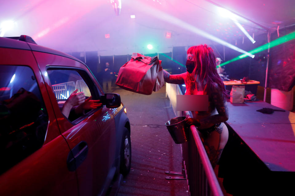 Dancer Elle Stanger serves takeaway food in coronavirus protective equipment at Portland socially distant strip club