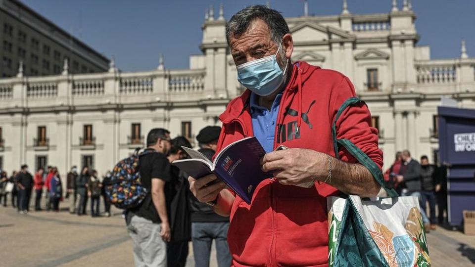 Un hombre lee un ejemplar de la propuesta de nueva Constitución en Chile
