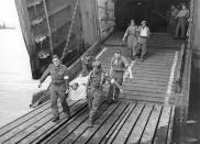 FILE - British troops wounded is assault on Normandy arrive back in Britain. Wounded British troops leaving the landing ship on which they were brought back from France, June 14, 1944. (AP Photo, File)