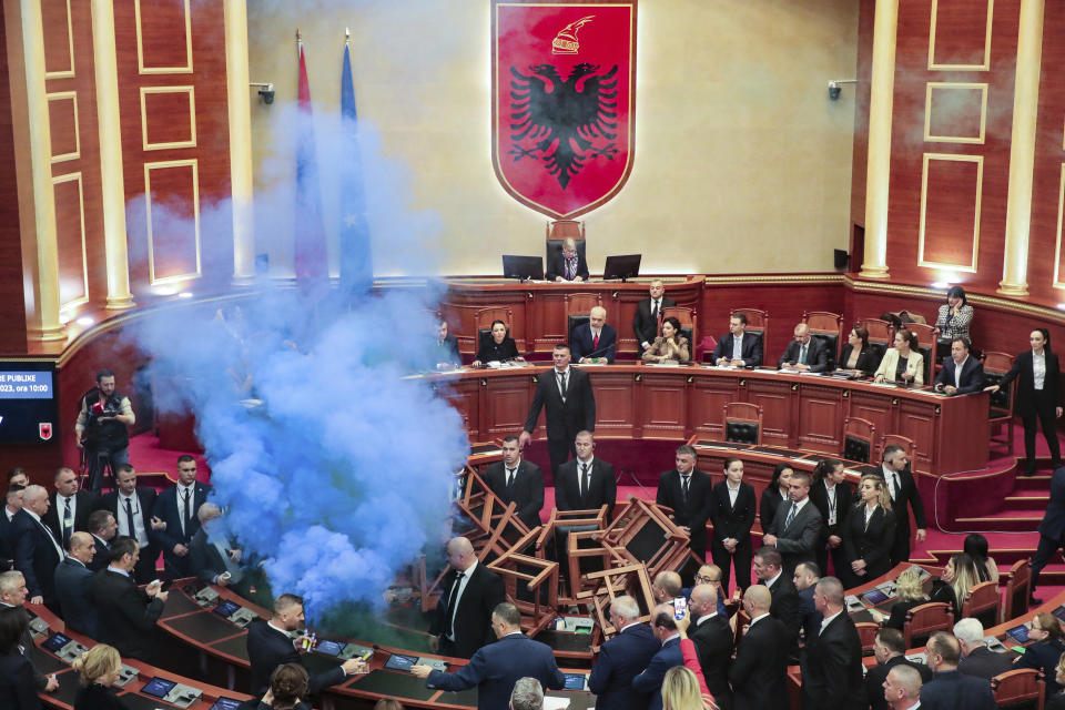 Democratic lawmakers throw flares during a parliament session in Tirana, Albania, Thursday Dec. 7, 2023. The Albanian Parliament on Thursday passed the annual budget and other draft laws in a disrupted vote from the opposition using flares and noise to protest against what they consider as an authoritarian rule from the governing Socialist Party. (AP Photo/Armando Babani)