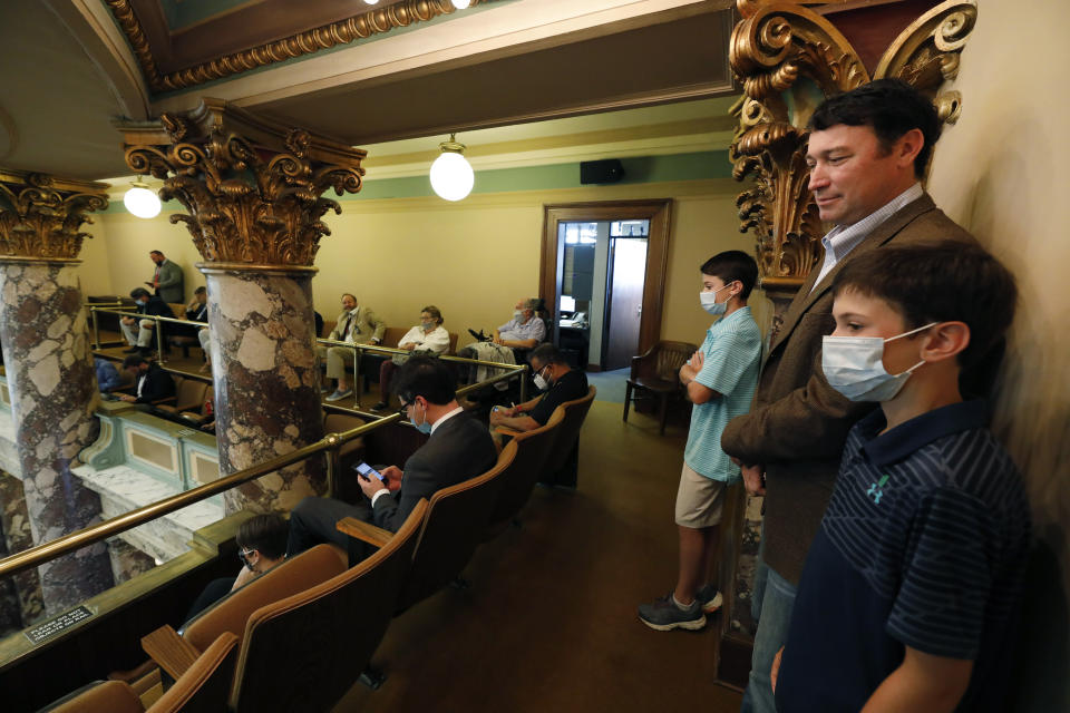 New Mississippi Department of Public Safety director Sean Tindell, second from right, stands with his sons, Sam, 12, right, and J.T. 10, as they observe the Senate vote on conference committee bills, Saturday, June 27, 2020 at the Capitol in Jackson, Miss. The family had hoped to see debate over suspending the rules so as to consider legislation changing the current Mississippi state flag. The current flag has in the canton portion of the banner the design of the Civil War-era Confederate battle flag, that has been the center of a long-simmering debate about its removal or replacement. (AP Photo/Rogelio V. Solis)