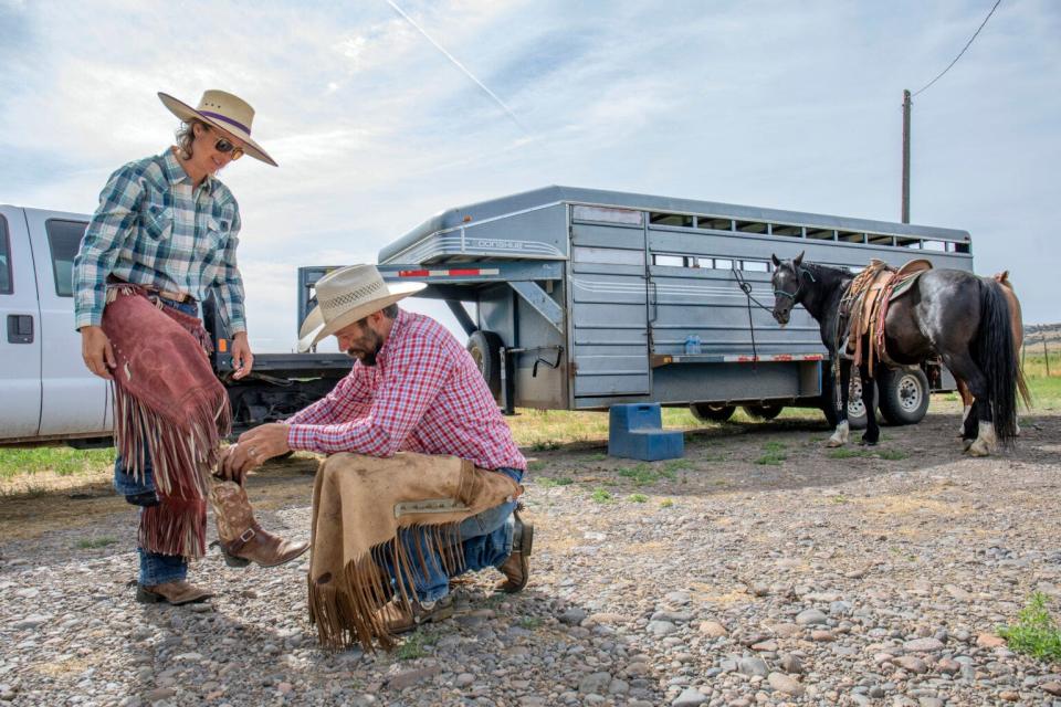 Kyler Brown helps wife Emily Brown put on boots before the cattle drive the morning of June 21, 2022.