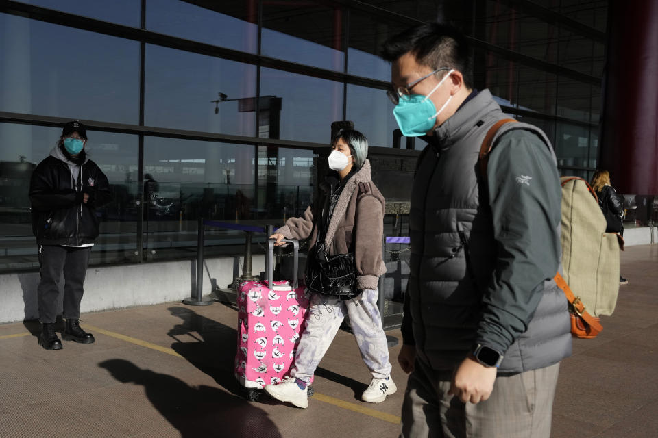 Passengers wearing masks arrive at the Capital airport terminal in Beijing, Tuesday, Dec. 13, 2022. Some Chinese universities say they will allow students to finish the semester from home in hopes of reducing the potential of a bigger COVID-19 outbreak during the January Lunar New Year travel rush. (AP Photo/Ng Han Guan)